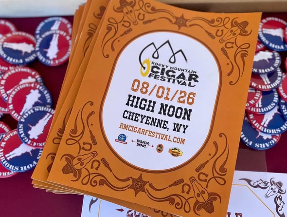 Stack of orange Rocky Mountain Cigar Festival 2026 flyers with western-style scrollwork, listing the August 1st date, Cheyenne, Wyoming location, and festival website